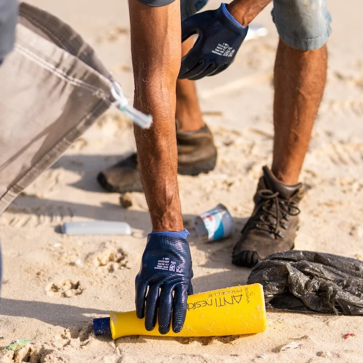 A person collecting plastic from the beach